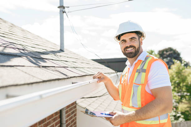 A man in a hard hat, holding a clipboard, standing on the steps of an old rundown house.